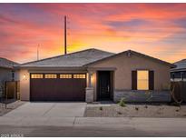 Charming single-story home with a two-car garage, stone accents, neutral paint, and a well-maintained front yard at sunset at 37399 W San Sisto Ave, Maricopa, AZ 85138