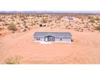 An aerial view of a single-story home with a gray roof and light blue siding situated in a desert landscape at 52002 W Sotol Rd, Maricopa, AZ 85139