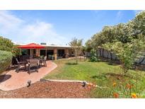 Landscaped backyard featuring patio with umbrella-covered seating and lush green grass at 7611 E Pasadena Ave, Scottsdale, AZ 85250