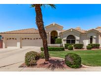 Charming home showcasing a manicured lawn, lush landscaping, and a three-car garage at 7648 W Mauna Loa Ln, Peoria, AZ 85381
