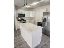 Modern kitchen with white cabinets, stainless steel appliances, island, and stylish lighting at 138 E Monte Way, Phoenix, AZ 85042