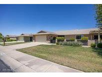 Charming single-story home with a well-manicured lawn, attached garage, and inviting curb appeal on a sunny day at 19018 N Concho Cir, Sun City, AZ 85373