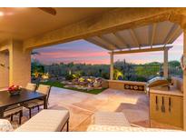 Inviting outdoor patio with built-in grill, waterfall feature, and serene desert views at sunset at 28375 N 130Th Dr, Peoria, AZ 85383