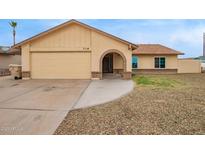 Charming single-story home featuring a tan exterior, an arched entryway, and a two-car garage at 7114 W Oregon Ave, Glendale, AZ 85303