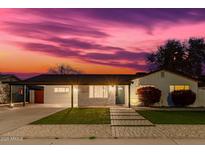 Charming home featuring a covered carport, a well-kept lawn and a beautiful pink and purple sunset at 7308 E Diamond St, Scottsdale, AZ 85257