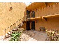 Tan building with stairs leading up to second floor condos and small patio with a bench for residents at 8500 E Indian School Rd # 233, Scottsdale, AZ 85251