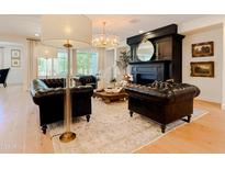 Elegant living room with hardwood floors, a black fireplace, and stylish leather seating under a modern chandelier at 10344 E Trillium Ave, Mesa, AZ 85212