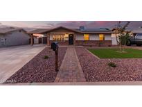 Inviting single-story home featuring solar panels, brick accents and a well-manicured, low maintenance front yard at 126 E Mclellan Rd, Mesa, AZ 85201