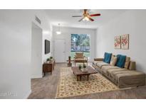 Cozy living room featuring a ceiling fan, comfortable seating, and natural light from a large window at 13424 N Emberwood Dr, Sun City, AZ 85351