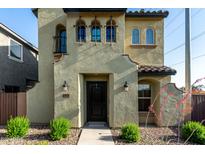 Stucco home featuring an elegant front door, stylish sconces, and desert landscaping at 17970 N 114Th Ln, Surprise, AZ 85378