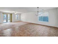 Spacious living room with tiled flooring, a chandelier, and ample natural light from the large windows at 17985 W Ivy Ln, Surprise, AZ 85388