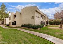 Low angle view of exterior with nice landscaping, and green lawns and a sidewalk leading to the building at 3119 W Cochise Dr # 111, Phoenix, AZ 85051