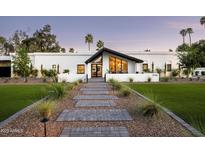 Stunning modern home with a white exterior, a black roof, and a beautifully landscaped front yard at 9733 E Clinton St, Scottsdale, AZ 85260