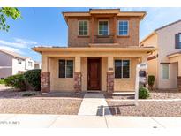 Charming two-story home featuring a cozy front porch and a small balcony on the second floor at 10055 E Isabella Ave, Mesa, AZ 85209