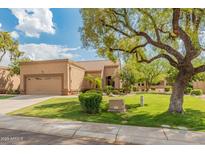 Charming single-story home featuring a well-manicured lawn, mature shade tree, and a neutral color palette at 19874 N 90Th Ave, Peoria, AZ 85382