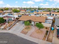 Charming single-story home featuring desert landscaping, a covered carport, and mature trees in a well-maintained neighborhood at 2217 N 51St Ln, Phoenix, AZ 85035