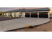 Modern home boasting a three-car garage and a well-lit driveway at dusk at 25450 W Pueblo Ave, Buckeye, AZ 85326