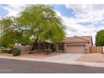 Single-story home with a beige exterior, tile roof, desert landscaping, and mature shade tree in front yard at 345 S Buena Vista Ave, Gilbert, AZ 85296