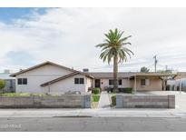 Charming single-story home with a palm tree, block fence, and covered parking at 6445 W Windsor Blvd, Glendale, AZ 85301