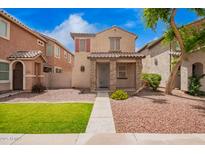 Charming two-story home featuring stone accents, a tiled roof, and a well-maintained, low-water landscape at 10 N 87Th Dr, Tolleson, AZ 85353