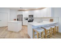 Modern kitchen boasts white cabinets, stainless steel appliances, an island, and stylish bar stool seating at 2511 W Queen Creek Rd # 374, Chandler, AZ 85248