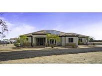 Single story home with desert landscaping, gravel drive, tile roof, solar panels and covered front porch at 2751 N Ralston Rd, Maricopa, AZ 85139