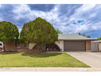 Charming single-story home with a well-manicured lawn and mature landscaping and attached two car garage at 6869 E Flossmoor Ave, Mesa, AZ 85208