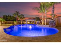 Stunning backyard pool with water feature, cabana, and lush tropical landscaping perfect for entertaining at 1179 E Regent Dr, Gilbert, AZ 85298