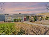 Charming single-story home with lush greenery, a brick facade, and a red front door under a colorful sky at 1712 E Montebello Ave, Phoenix, AZ 85016