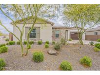 Charming home exterior featuring desert landscaping with stone accents and mature trees at 18624 W Cathedral Rock Dr, Goodyear, AZ 85338