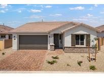 Charming single-story home featuring a brick driveway, two-car garage, and desert landscaping at 25616 N 148Th Dr, Surprise, AZ 85387