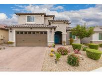 Beautiful two-story home featuring a well-manicured front yard with vibrant desert landscaping and a charming blue front door at 28931 N 64Th Dr, Phoenix, AZ 85083