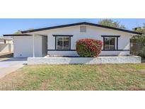 Charming home with fresh white paint, black trim, and a vibrant flowering bush at 340 W Riviera Dr, Tempe, AZ 85282