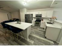 Bright, modern kitchen with stainless steel appliances, quartz counters, and breakfast bar seating at 6920 S 46Th Dr, Laveen, AZ 85339