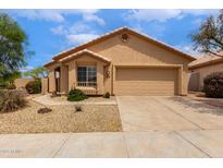 A tan one-story home featuring a well-kept yard and a two-car garage under a blue sky at 11808 E Clinton St, Scottsdale, AZ 85259