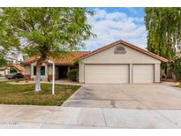 Charming single-story home with a well-manicured front yard, three-car garage, and terracotta roof tiles at 1333 E Bermuda Bay Ct, Gilbert, AZ 85234
