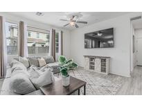 Bright living room with gray sectional, ceiling fan, stylish console and large windows offers cozy relaxation at 14870 W Encanto Blvd # 1061, Goodyear, AZ 85395