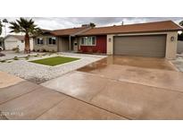 Charming single-story home featuring desert landscaping, a palm tree and a two car garage at 3021 E Shangri La Rd, Phoenix, AZ 85028
