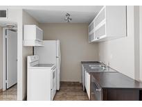Compact kitchen featuring white appliances, upper cabinets and a stainless steel sink at 5525 E Thomas Rd # R11, Phoenix, AZ 85018