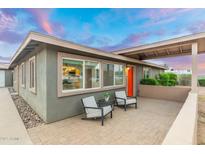 Charming home featuring an inviting front porch with stylish seating and a vibrant orange door at 717 E Palmaire Ave, Phoenix, AZ 85020