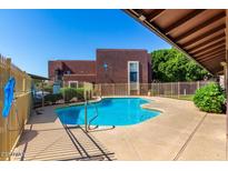Community pool with clear blue water surrounded by fence and concrete patio at 16602 N 25Th St # 129, Phoenix, AZ 85032
