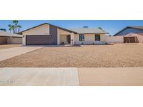 Charming single-story home features a gravel yard, gray garage door, and modern architecture under a clear sky at 17040 N 39Th Ave, Glendale, AZ 85308