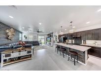 Open concept living room featuring a modern kitchen and a comfortable seating area with rustic wood accents at 22282 N 184Th Ln, Surprise, AZ 85387