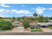 Charming single-Gathering home featuring a well-manicured lawn, mature trees, and a mountain backdrop under a bright blue sky at 3046 E Glenrosa Ave, Phoenix, AZ 85016