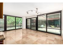 Bright living room featuring large windows, travertine floors, and an unique contemporary light fixture at 4808 N 24Th St # 231, Phoenix, AZ 85016