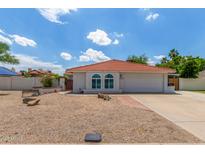 Charming single-story home featuring a red tile roof, arched windows, and a low-maintenance desert landscape at 4953 W Acoma Dr, Glendale, AZ 85306