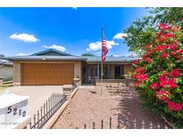 Charming brick home featuring an American flag, desert landscaping, and beautiful bougainvillea at 5210 W Ironwood Dr, Glendale, AZ 85302