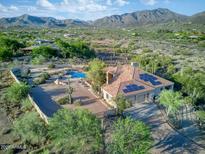Stunning aerial view of a desert home, featuring a pool, tile roof, and solar panels against a mountain backdrop at 6524 E Rockaway Hills Dr, Cave Creek, AZ 85331