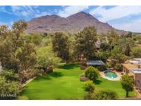 Expansive backyard with lush lawn, mature trees, and a sparkling pool, set against a scenic mountain backdrop at 6735 E San Juan Ave, Paradise Valley, AZ 85253