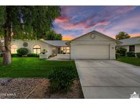 Charming single-story home featuring a two-car garage, well-maintained lawn, and desert landscaping under a vibrant sunset at 13023 W Tangelo Dr, Sun City West, AZ 85375